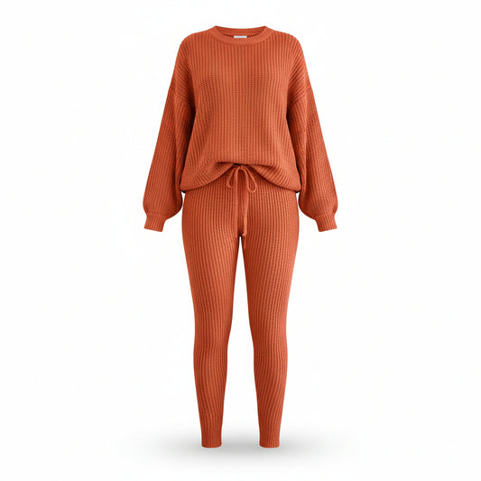 Person wearing an orange knit outfit with a beige sofa and white curtains in the background
