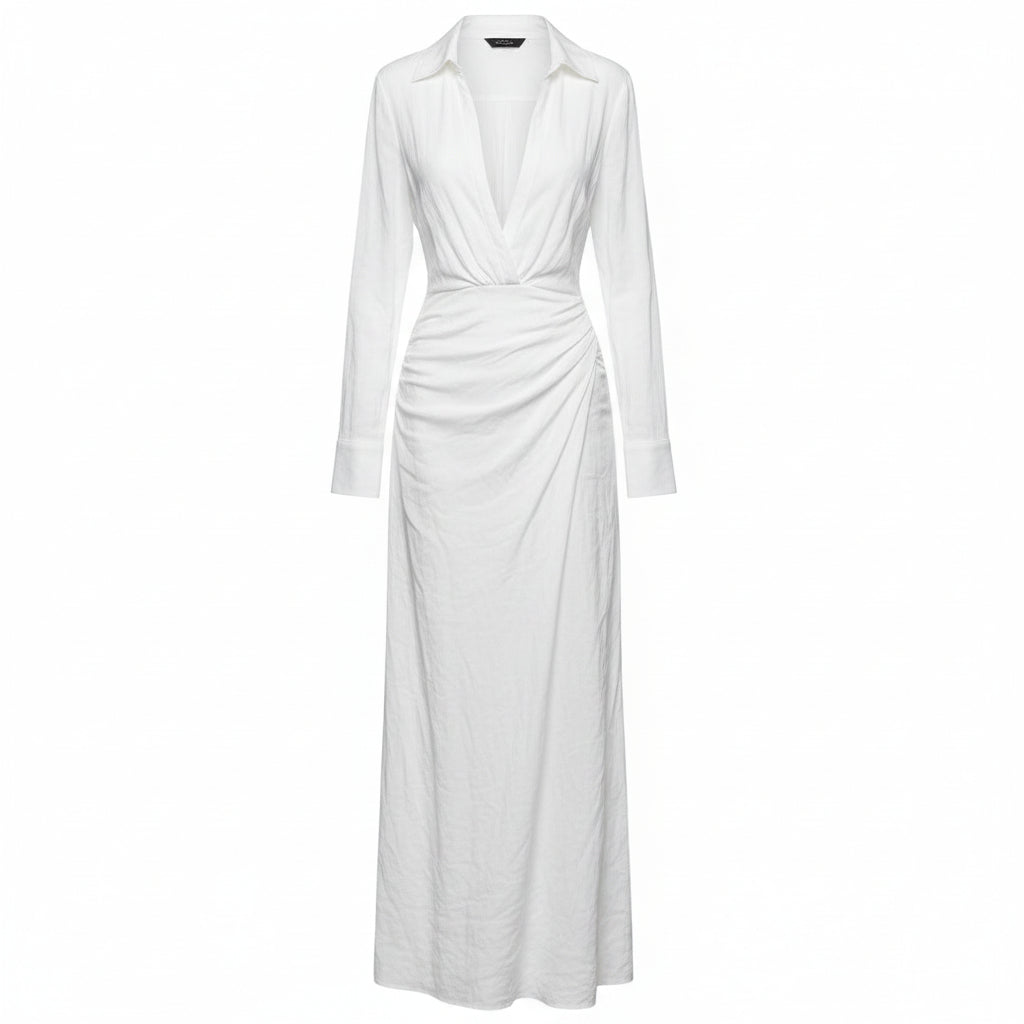 Woman wearing a white dress with a brown belt and holding a woven bag against a plain background