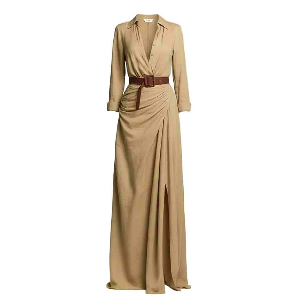 A woman models a flowing tan maxi shirt dress with a deep V-neck, long sleeves rolled to the forearm, and a brown leather belt. She is carrying a woven straw tote bag and wearing flat brown sandals, set against a textured light gray concrete wall.