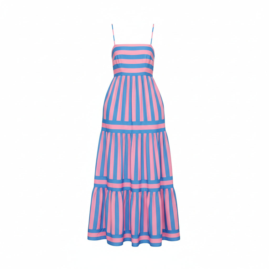 Woman wearing a pink and blue striped dress standing in a room with a vase of sunflowers.