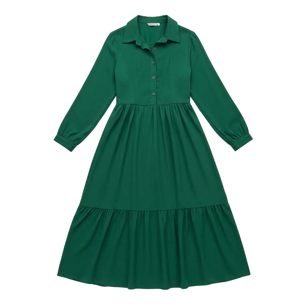 Woman wearing a green dress with long sleeves in a room with a white couch and plant.