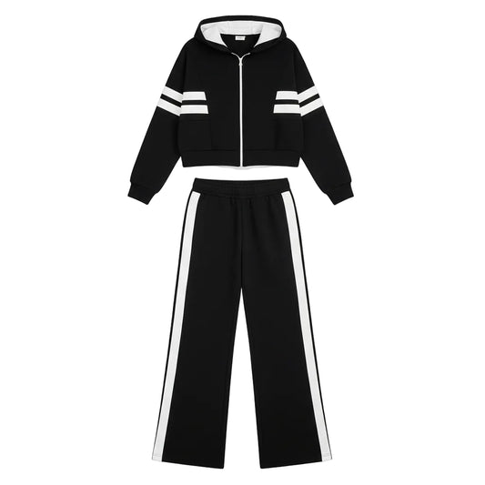 Person wearing a black tracksuit with white stripes in an indoor setting.